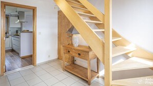 A modern kitchen with white cabinets and a wooden staircase. - Quiet Villa with Hot Tub & Sauna (Somme-Leuze)