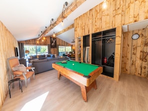 Quarto aconchegante com mesa de bilhar, sofá e área de refeições.