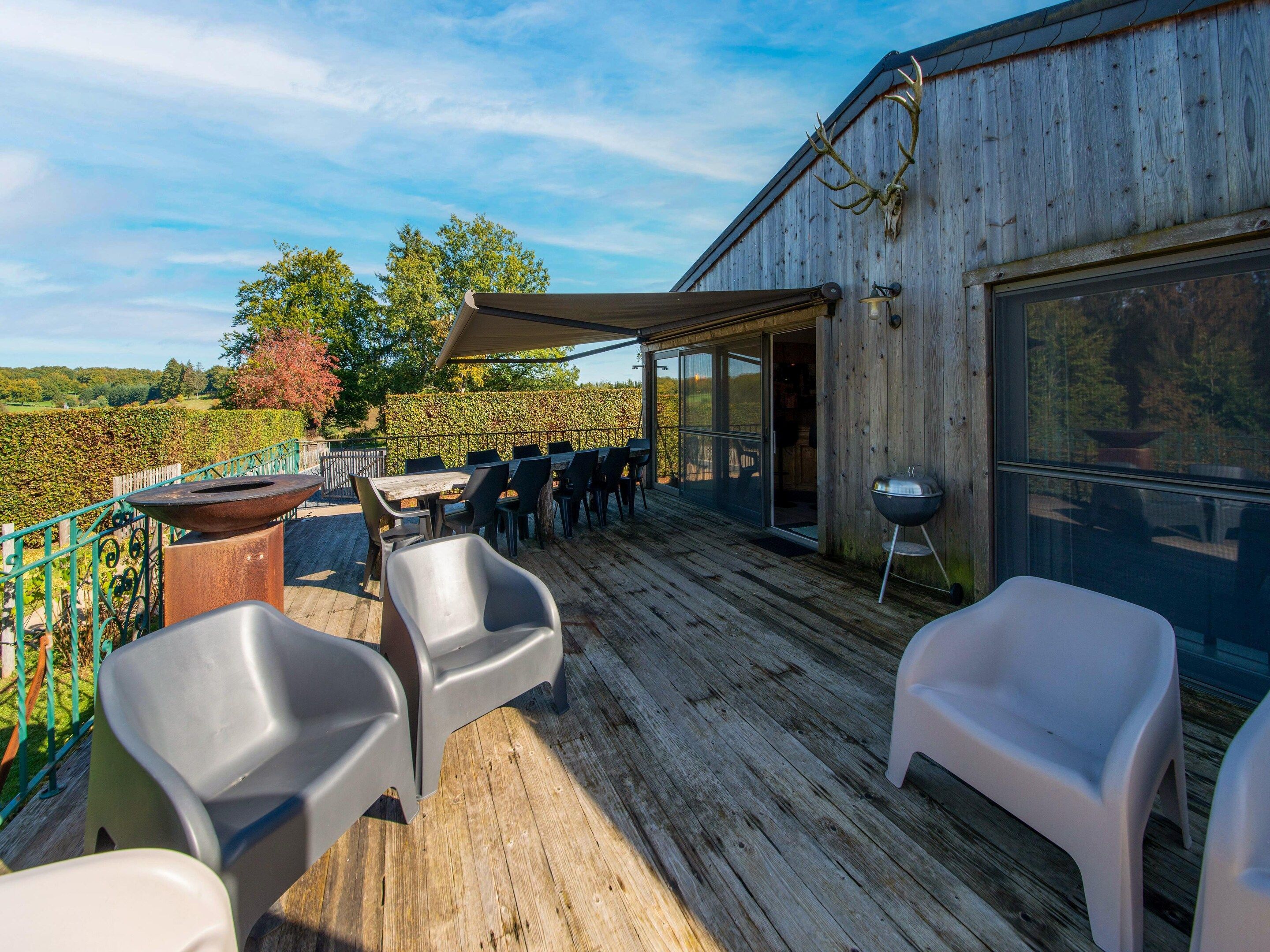 An outdoor patio with a wooden deck, a grill, and a table with chairs.