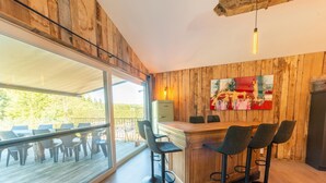 Eine moderne Küche mit einer Holzvertäfelung, einem großen Fenster und einer Bar mit Hockstühlen.