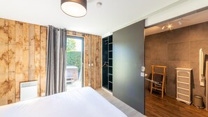 A modern bedroom with a large bed, wooden panel walls, a sliding door to a balcony, and a built-in wardrobe. - Lush Chalet Near Lake of Butgenbach (Buellingen)