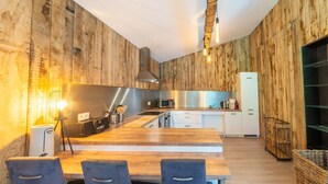 A modern kitchen with wooden paneling, a stainless steel range hood, a microwave, and a white refrigerator. - Lush Chalet Near Lake of Butgenbach (Buellingen)
