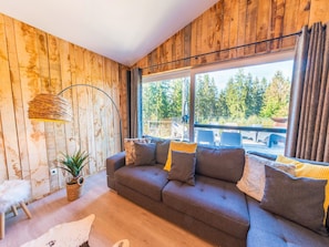 Un salón acogedor con un sofá, una lámpara de pie y vistas al exterior.