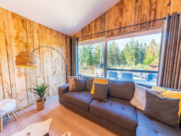 A cozy living room with a sofa, a floor lamp, and a view of the outdoors.