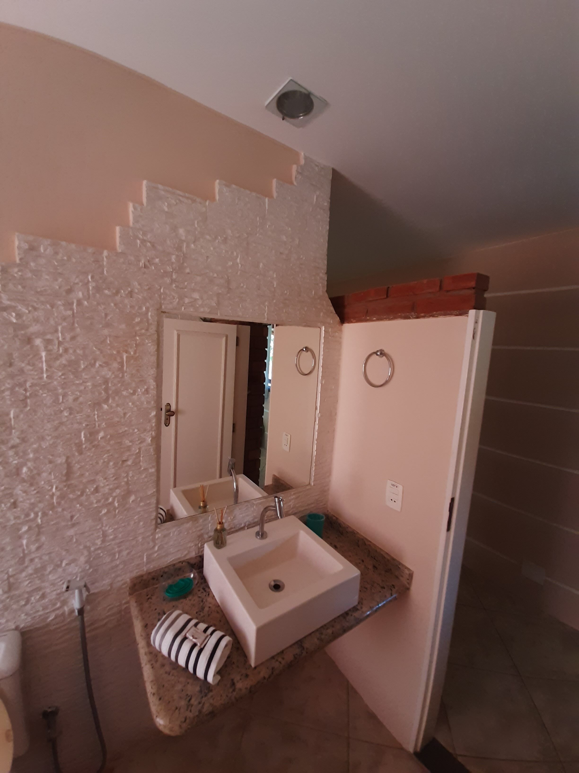 A bathroom with a white sink, two mirrors, a towel rack, and a shower area.