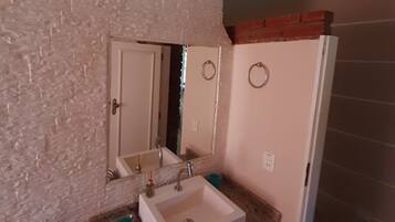 A bathroom with a white sink, two mirrors, a towel rack, and a shower area.