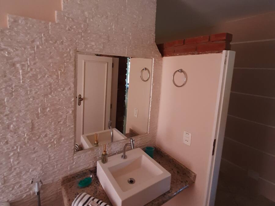 A bathroom with a white sink, two mirrors, a towel rack, and a shower area.
