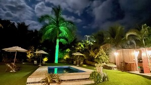 A backyard with a swimming pool, palm trees, and a wooden structure. - Bacana Hotel Boutique (Búzios)