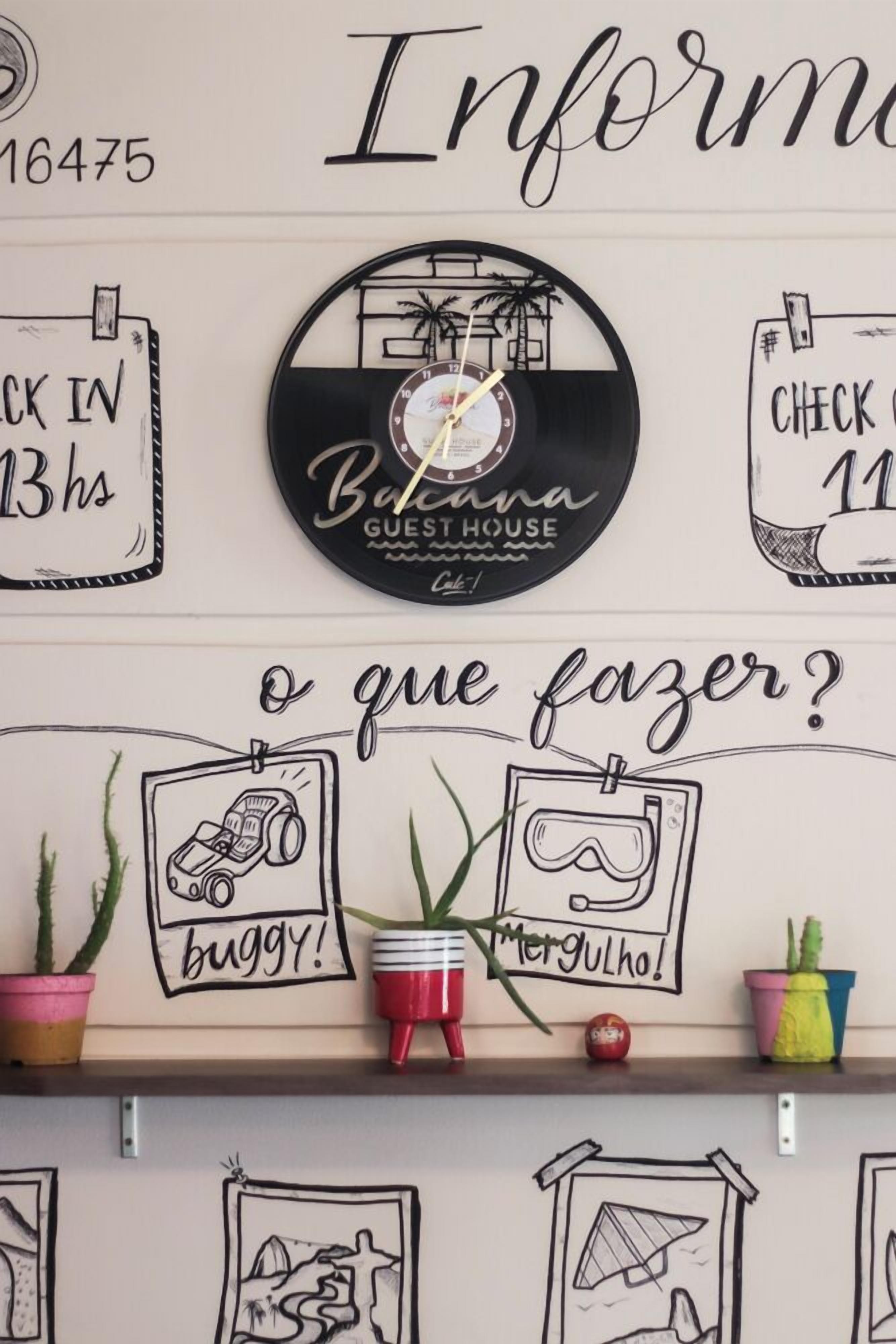 Eine Wand mit einer Uhr, einem Schild mit der Aufschrift "Check in 13 hrs" und einem Schild, das "Guest House" zeigt.