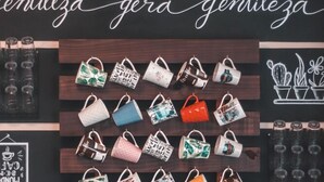A display of colorful bags and coffee products on a wooden shelf. - Bacana Hotel Boutique (Búzios)