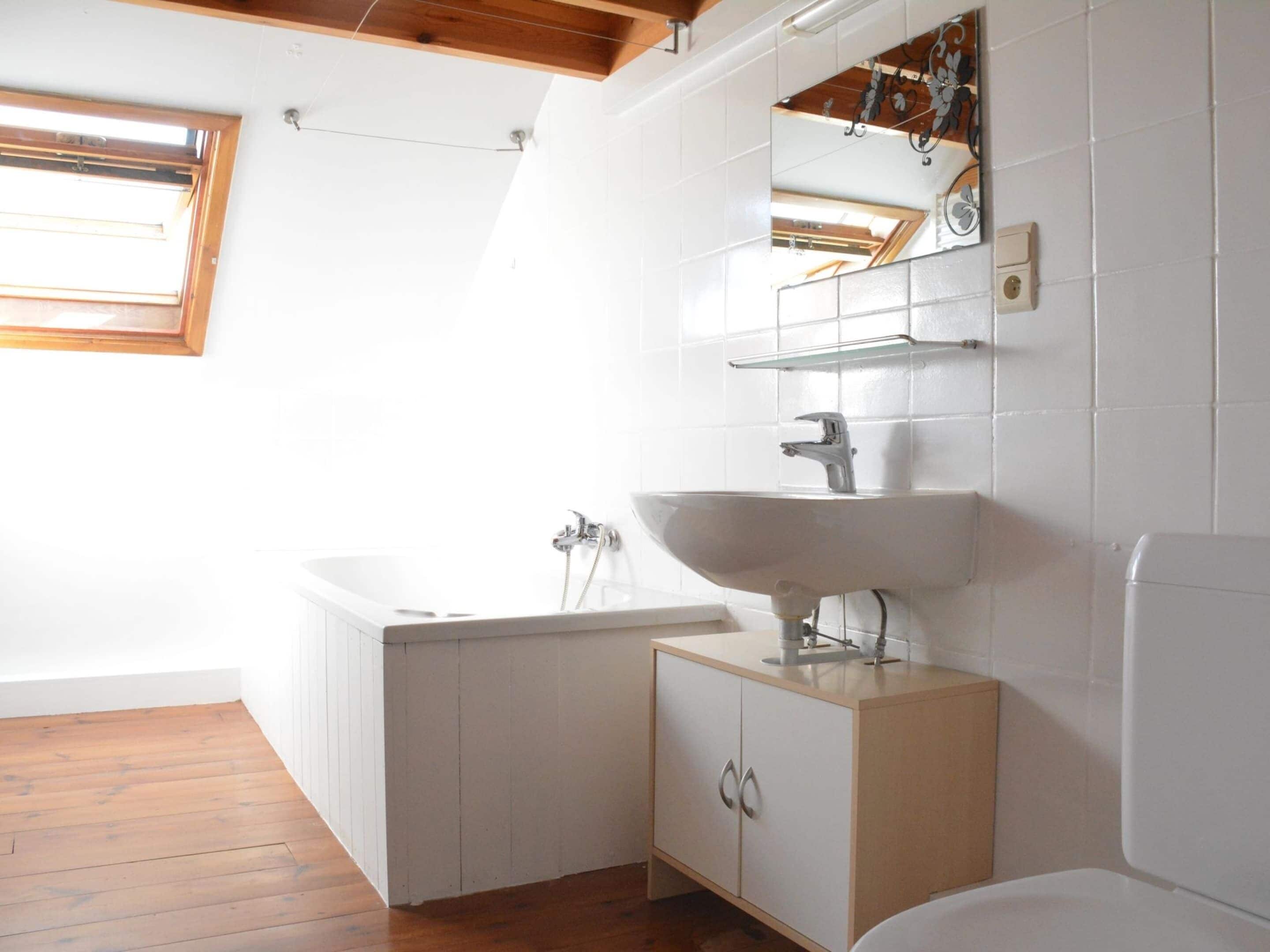 Un baño moderno con una bañera independiente, un lavamanos con espejo y techo de madera.