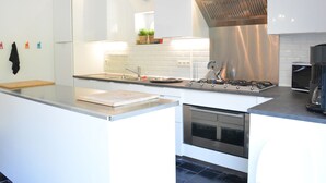 A modern kitchen with white cabinetry, a stainless steel range hood, a built-in oven, and a clock on the wall. - Family Retreat, Forested Anhee (Anhée)