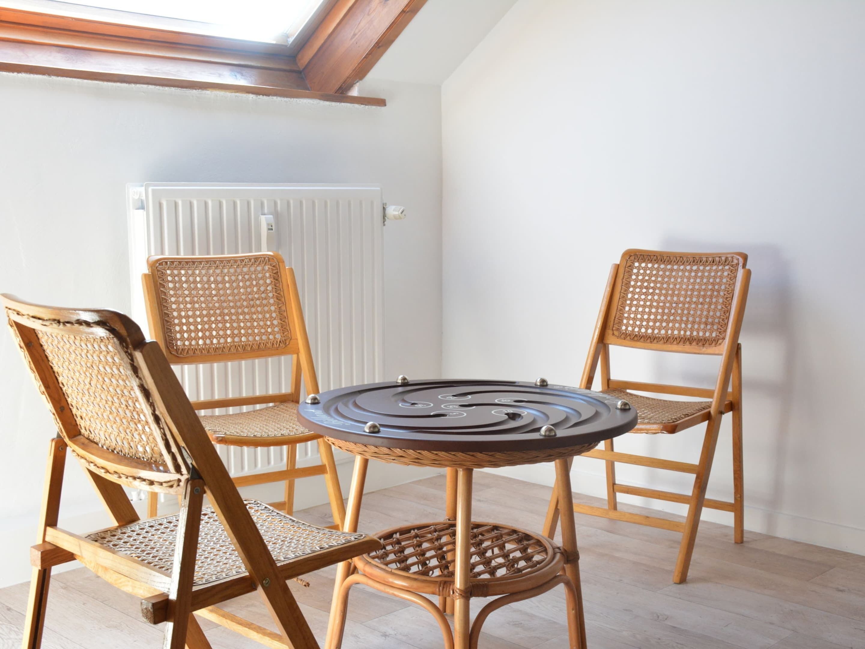 A corner room with a round table and four wicker chairs.