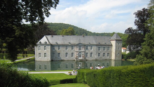 A large stone building with a reflective pond in front, surrounded by well-maintained hedges and trees. - Family Retreat, Forested Anhee (Anhée)