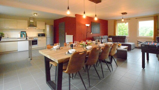 A spacious kitchen with a dining area, featuring a wooden table, chairs, and a foosball table. - Elegant Child Friendly Villa in Berismenil near Forest (La Roche-en-Ardenne)