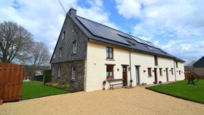 A two-story building with a sloped roof, a gravel driveway, and a wooden fence. - Cottage Near Spa F1 Circuit (Stavelot)