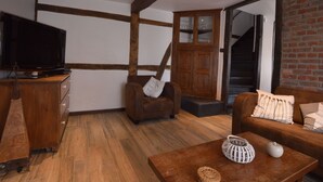 A modern living room with exposed wooden beams, a television, a sofa, and a coffee table. - Cottage Near Spa F1 Circuit (Stavelot)