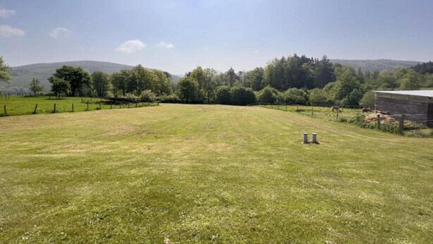 A grassy field with a fenced area, a small building, and trees in the background. - Peaceful Garden Home, Chevron (Stoumont)