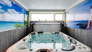 Een kuub met uitzicht op de oceaan door een raam, omringd door houten wanden en murals in tropisch thema.
