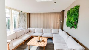 Een moderne woonkamer met een hoekbank, een houten salontafel en een verticale wand vol groen.