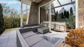 Een modern zitgedeelte buiten, met een glazen deur naar een terras.