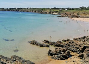 A coastal beach with clear water, rocky shoreline, and distant houses. - Holiday Home Near Brittany Beaches (Clohars-Carnoët)