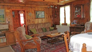 A wooden cabin interior with a sofa, armchairs, a dining table, and a bed. - Boutique Apartment in Valais With Balcony (Guttet-Feschel)