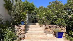 A stone staircase leading up to a building, surrounded by lush greenery and potted plants. - Modern Villa With Private Pool (Pouzols-Minervois)