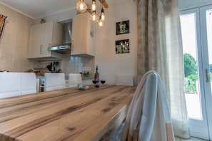 A kitchen with a wooden table, white cabinets, and hanging pendant lights. - Modern Villa With Private Pool (Pouzols-Minervois)