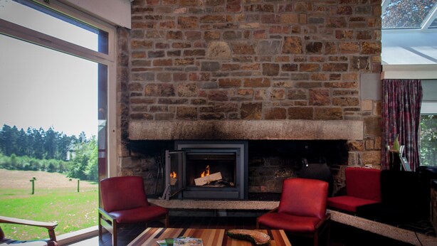 Una habitación acogedora con chimenea de piedra, dos sillones rojos y una mesa de centro de madera.