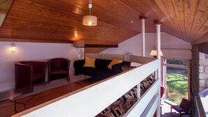 Un interior moderno con techo de madera, un sofá con cojines estampados y vistas a un jardín a través de una ventana.