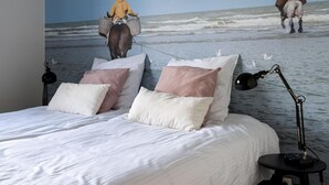 A bedroom with a large bed, pillows, a nightstand, and a wall mural of a beach scene. - Charming Villa With Indoor Swimming Pool, Near the Beach and Town Centre (Koksijde)