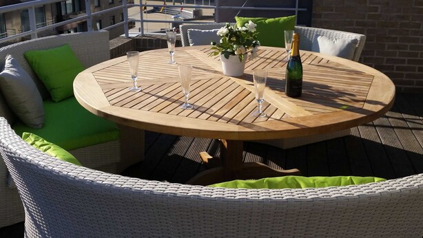 A round wooden table with a bottle of champagne and three glasses on a balcony with wicker furniture and green cushions. - Penthouse With 2 Terraces and Sea/casino Views (Middelkerke)