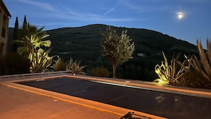 Ein Swimmingpool mit Blick auf einen Hügel und ein Gebäude im Hintergrund.