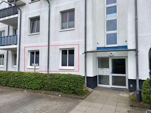 Ein mehrgeschossiges Gebäude mit einer flachen Fassade, einem verschlossenen Eingang und einem sichtbaren Hydranten.