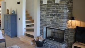 A stone fireplace with a TV on a stand, wooden stairs, and a blue cabinet. - Chalet in La Tzoumaz Near Ski Lift (Riddes)