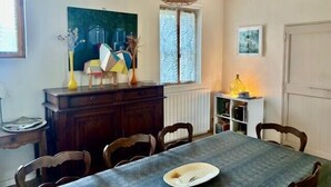 Un coin repas comprenant une table, des chaises, un buffet et une fenêtre agrémentée de rideaux à motifs.