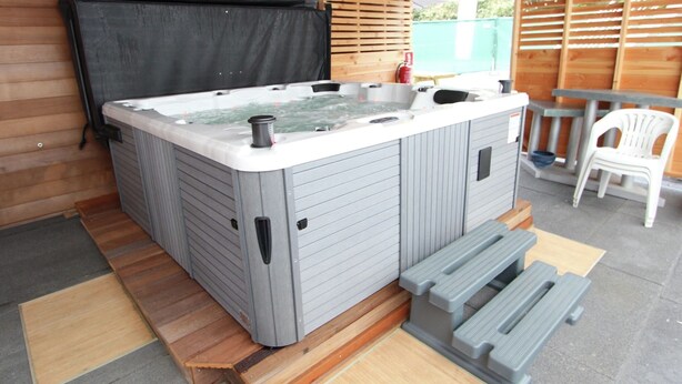 Un jacuzzi con muelle de madera y una mesa con sillas.