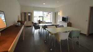 Una cocina moderna con comedor, televisor y un amplio ventanal.