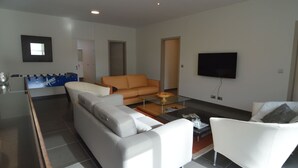 Una sala de estar moderna con un sofá, un sillón y una mesa de fútbol.