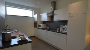 Una cocina moderna con electrodomésticos de acero inoxidable, armarios blancos y un ventanal que proporciona luz natural.