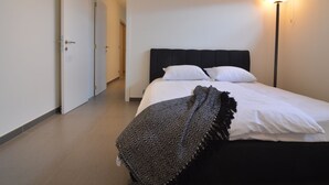 Una habitación de hotel con una cama, una lámpara de noche y una puerta que da a otra estancia.