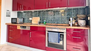 Una cocina moderna con armarios rojos, un microondas, un tostador y un lavamanos.