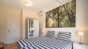 A bedroom with a bed, bedside tables, a mirror, a wardrobe, and a large forest-themed painting on the wall. - Villa in Escales With Private Pool (Escales)