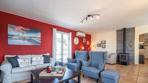 A living room with a red wall, a sofa, a coffee table, and a fireplace. - Villa in Escales With Private Pool (Escales)
