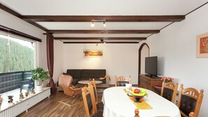 Ein Essbereich mit Holztisch, Stühlen, einer Couch und einem Fernseher.