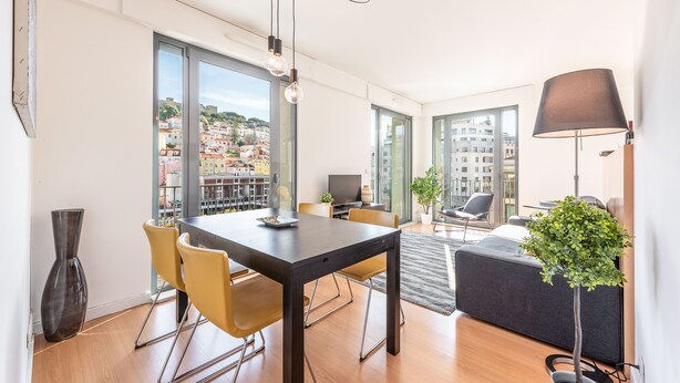 A modern living room with a dining area, large windows, and a view of the city. - Martim Moniz Luxury Apartment (Lisboa)