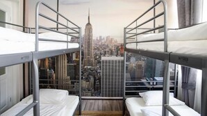 Una habitación con literas y un ventanal que ofrece vistas a la ciudad.