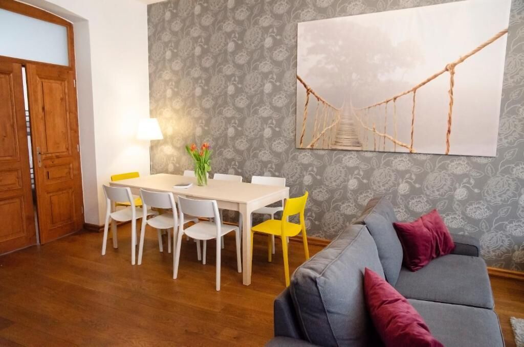 A dining area with a table and chairs, a sofa, and a wall with a framed picture.