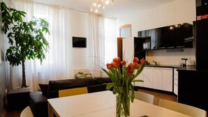 Una sala de estar moderna con una mesa de comedor, un sofá, una planta en maceta y un jarrón de tulipanes.